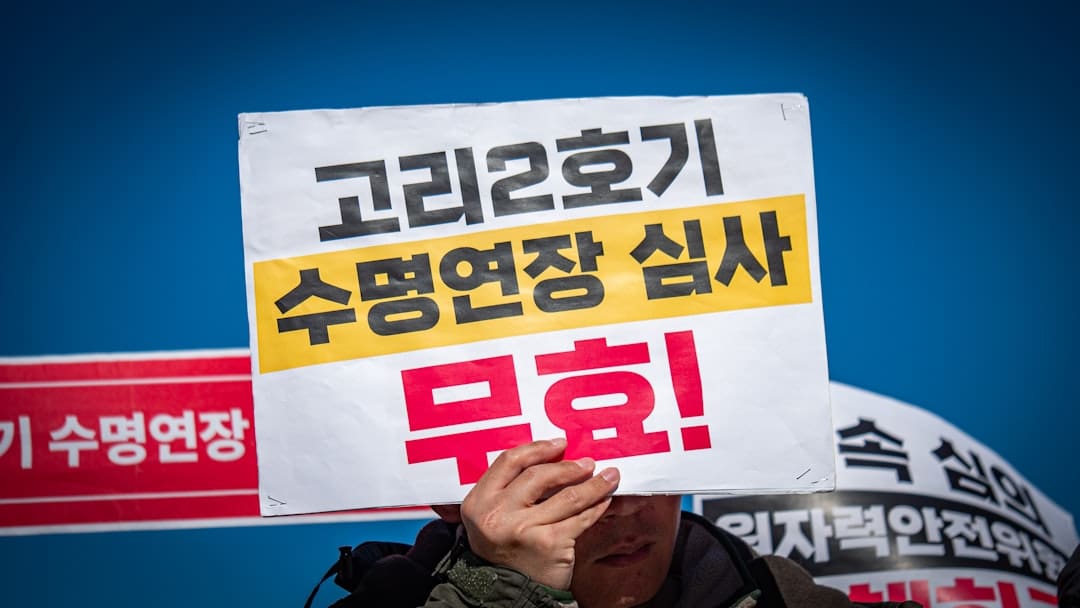 breed restrictions — Person holds sign protesting nuclear power plant operation.