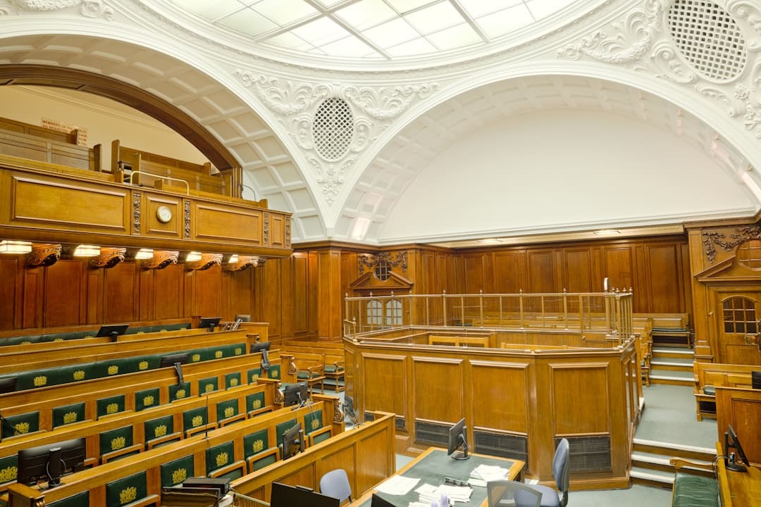 DOJ enforcement ADA — Empty ornate courtroom interior with wooden paneling and green seats.